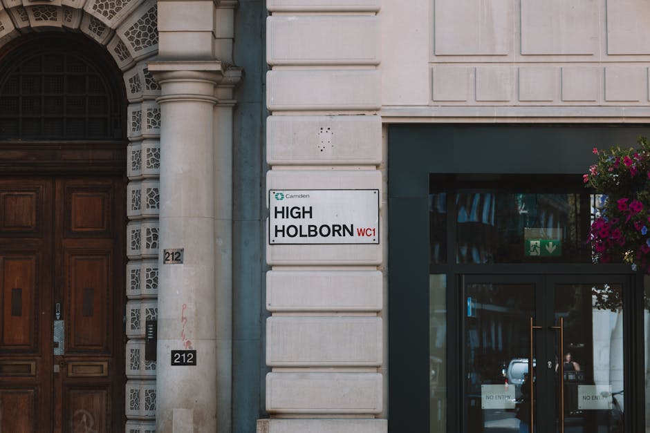 Close-up view of the exterior of a building on Clapham High Street during a house removal process, showing a white sign with black and red lettering indicating the address 'HIGH HOLBORN WC1' affixed t